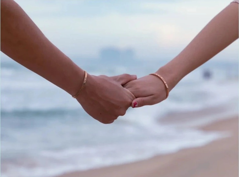 Two people holding hands on the beach